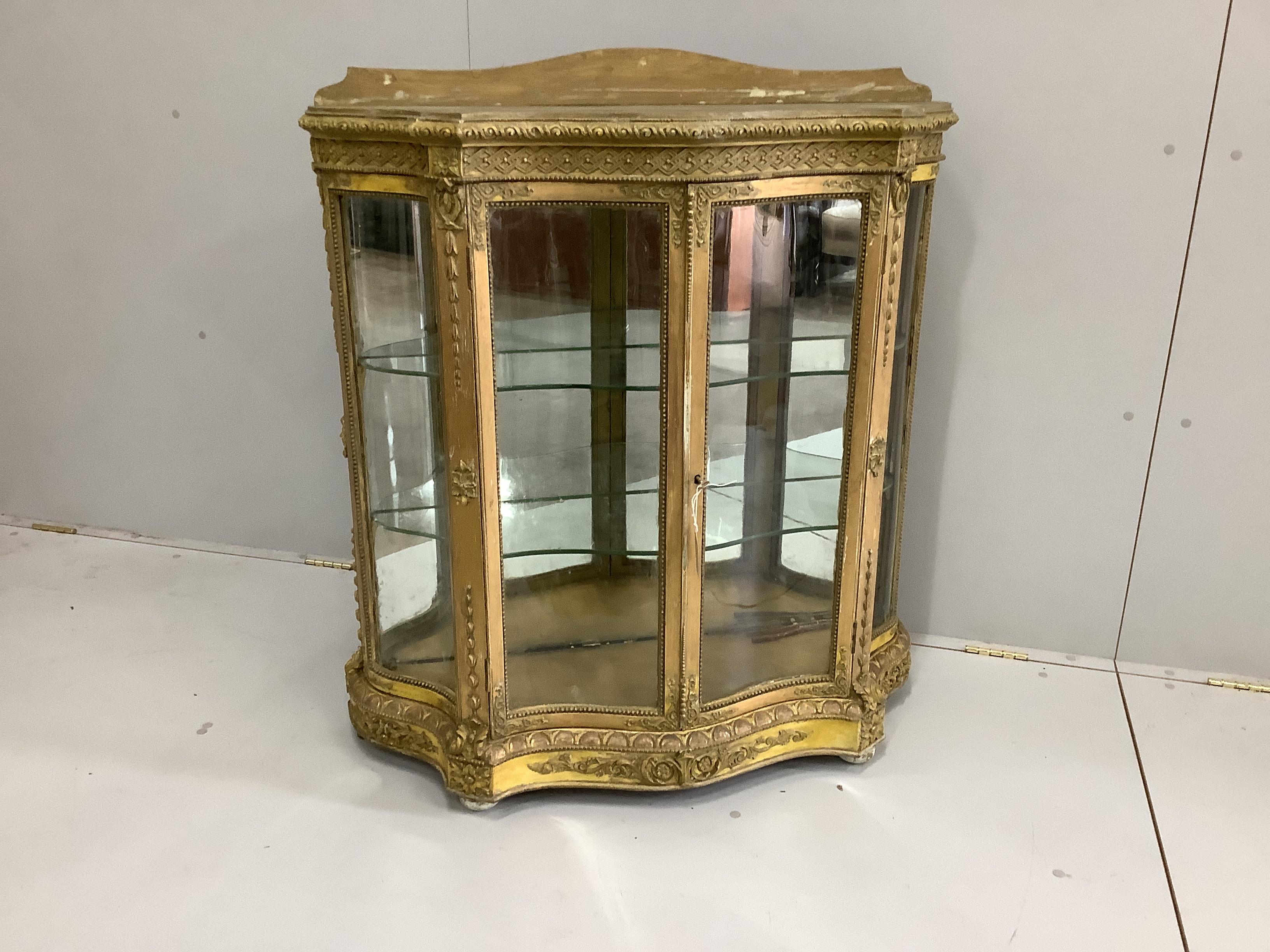 A Victorian giltwood and composition glazed serpentine side cabinet, width 92cm, depth 33cm, height 104cm